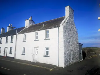 a white building with two chimneys on top of it at Traditional Cottage with Beautiful Views - Pass the Keys in Isle of Whithorn