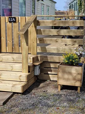 a wooden fence with a potted plant next to it at Forest Valley Holiday Home in Ballantrae