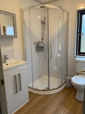 a bathroom with a shower with a sink and a toilet at The Woodhouse Cabin 8 in Moffat