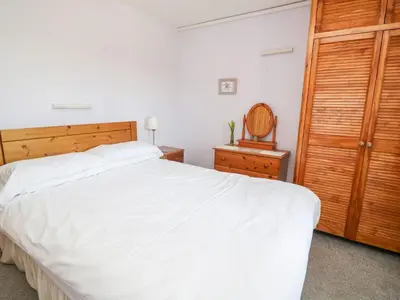 a bedroom with a large white bed and a wooden closet at Bramble Cottage in Keswick