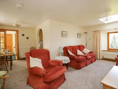 a living room with two red chairs and a table at Swallow's Nest in Keswick