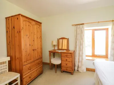 a bedroom with a wooden cabinet and a desk and a window at Swallow's Nest in Keswick