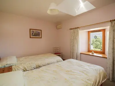 a bedroom with two beds and a window at Swallow's Nest in Keswick