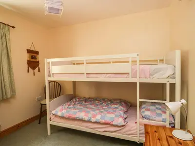 a white bunk bed in a room with a desk at Swallow's Nest in Keswick