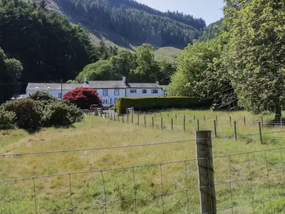 a white house in a field with a fence at Swallow's Nest in Keswick