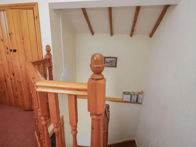 a room with a wooden staircase with a table at Wren's Nest in Keswick
