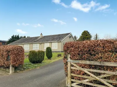 a house with a wooden gate and a hedge at Violet Bank in Cockermouth