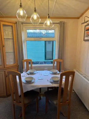 a dining room table with chairs and a window at Penny in Whithorn
