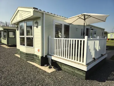 a small green house with an umbrella on the porch at Penny in Whithorn
