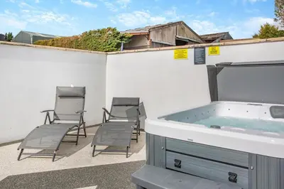 a hot tub on a patio with four chairs at 1 Bed in Cockermouth oc-s31514 in Embleton