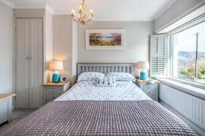 a bedroom with a bed and two windows and a chandelier at 2 Bed in Braithwaite oc-p31730 in Braithwaite