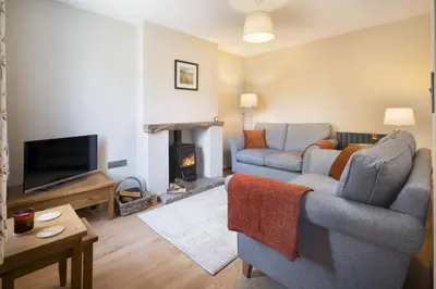 a living room with a couch and a fireplace at Riverside - Quaint County Cottage overlooking the Beck in Caldbeck