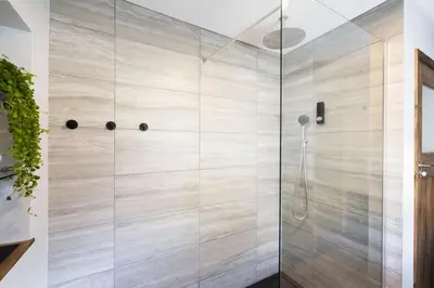 a shower with a glass door in a bathroom at Riverside - Quaint County Cottage overlooking the Beck in Caldbeck
