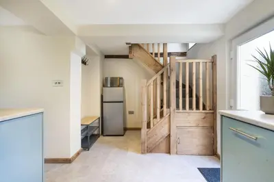 a kitchen with a staircase and a refrigerator at Riverside - Quaint County Cottage overlooking the Beck in Caldbeck