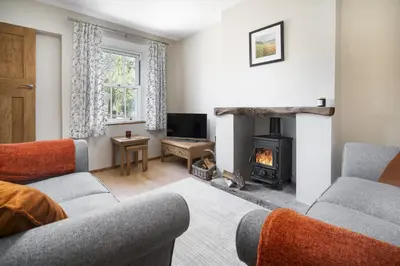 a living room with two couches and a fireplace at Riverside - Quaint County Cottage overlooking the Beck in Caldbeck