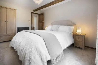 a bedroom with a white bed and a wooden cabinet at Riverside - Quaint County Cottage overlooking the Beck in Caldbeck