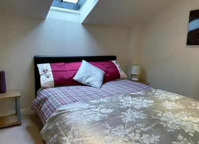 a bedroom with a bed with colorful pillows on it at 3 Telford Mews in Dumfries