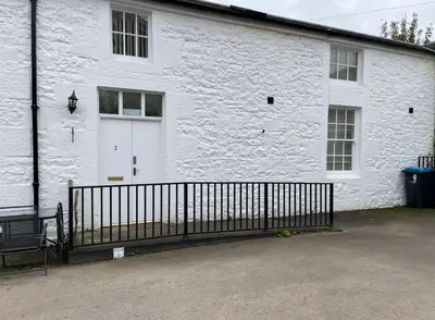 a white building with a gate and a white door at 3 Telford Mews in Dumfries