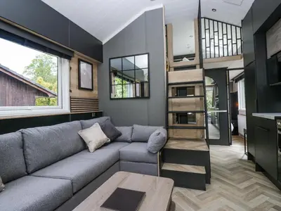 a living room with a couch and a book shelf at Sail Luxury Family Pod in Keswick