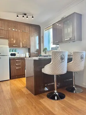 a kitchen with wooden cabinets and two bar stools at Saltayr in Ayr
