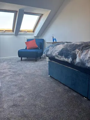 a bedroom with a bed and a couch and windows at Saltayr in Ayr