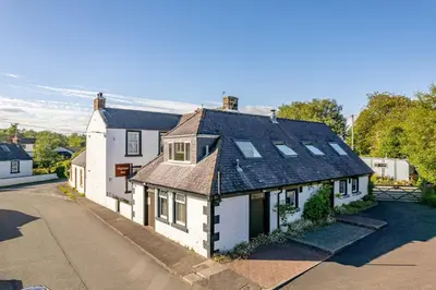 an old white house with solar panels on its roof at Hightae B&B in Hightae
