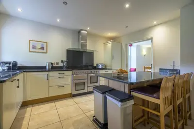 a large kitchen with a counter and chairs in it at The School at Mungrisdale in Penrith