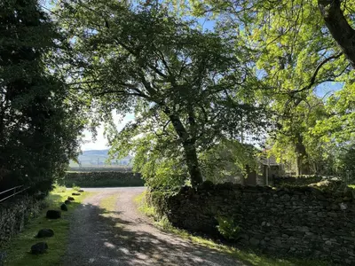 a road with a stone wall and a tree at The School at Mungrisdale in Penrith