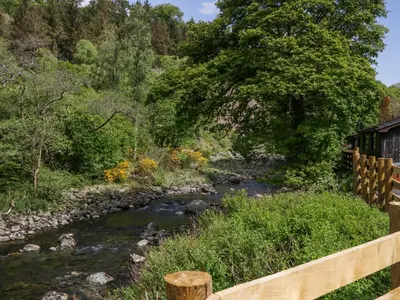 a river with a wooden fence next to a bridge at Dubs Luxury Family Pod in Keswick