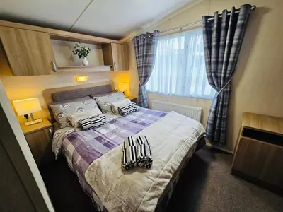 a small bedroom with a bed with blankets and pillows at The Canny View at Three Lochs Holiday Park in Balminnoch 3 bedroom sleeps upto 8 guests in Newton Stewart