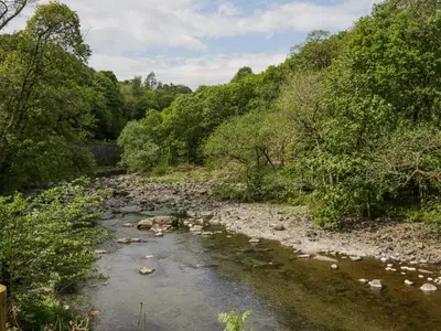 a river with rocks and trees on the side at Elter Luxury Pod in Keswick