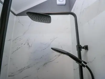a shower in a bathroom with a white marble wall at Lingy Luxury Family Pod in Keswick