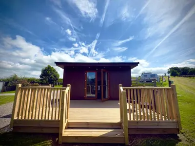 a small cabin with two benches on a deck at Country Cabin in Hesket Newmarket
