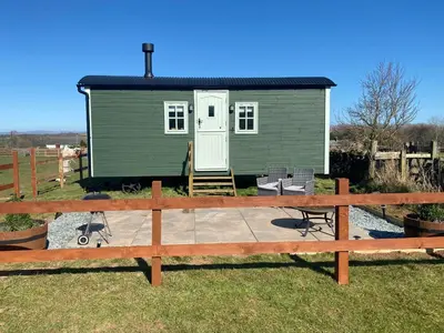 a green tiny house with a patio in the yard at Sunset Snug Shepherd hut in Penrith