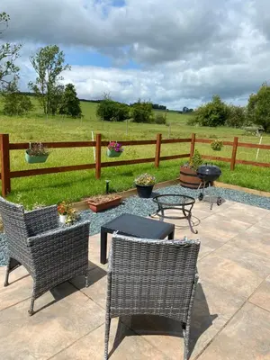 a patio with chairs and a table and a fence at Sunset Snug Shepherd hut in Penrith