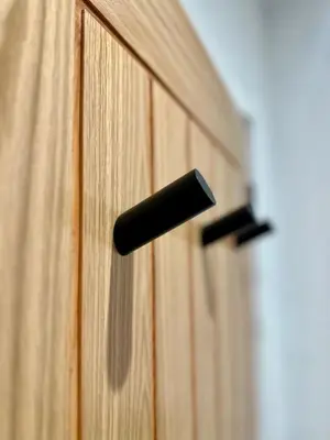 a black door handle on a wooden cabinet at The Byre, Summerhill Farm Stays in Balmaclellan