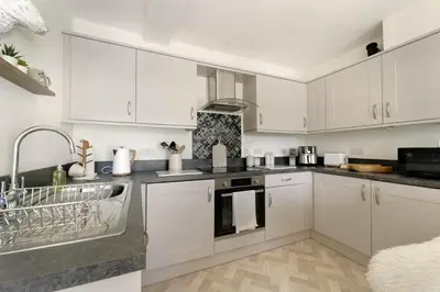 a kitchen with white cabinets and a sink at 6 Harney Peak in Portinscale