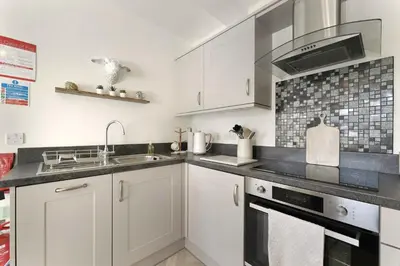 a kitchen with white cabinets and a sink at 6 Harney Peak in Portinscale