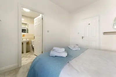 a white bedroom with a bed with towels on it at 6 Harney Peak in Portinscale