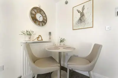 a table and two chairs and a clock on a wall at 6 Harney Peak in Portinscale