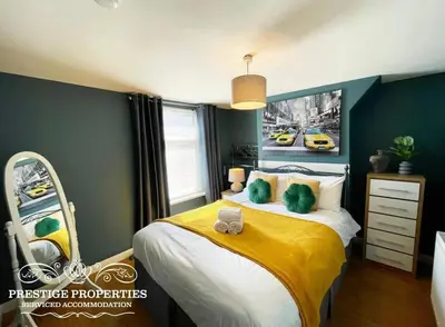 a bedroom with a large bed with a yellow blanket at Victoria Place by Prestige Properties SA in Workington