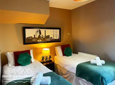 a room with two beds and a picture on the wall at Victoria Place by Prestige Properties SA in Workington