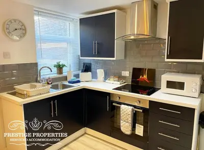 a kitchen with black cabinets and a microwave at Victoria Place by Prestige Properties SA in Workington