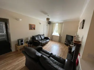 a living room with a leather couch and a television at Belton House Guest Rooms in Wanlockhead