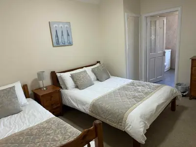 a bedroom with two beds and a table with a lamp at Belton House Guest Rooms in Wanlockhead
