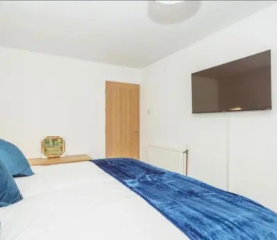 a bedroom with a bed with a tv on the wall at Caul View Apartment in Dumfries in Dumfries