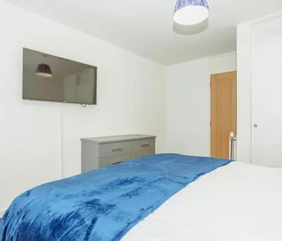 a white bedroom with a blue blanket on a bed at Caul View Apartment in Dumfries in Dumfries