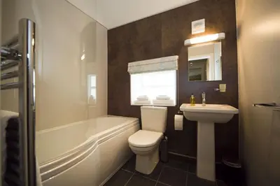 a bathroom with a sink and a toilet and a bath tub at Sandhills Farm in Bassenthwaite