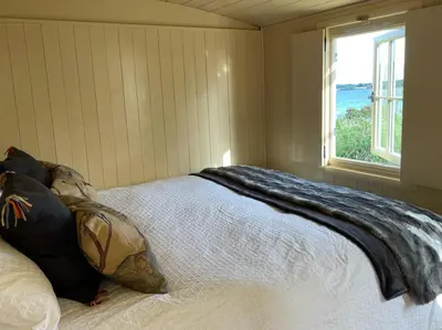 a bed with a blanket on it in a room with a window at The Secret Shepherds Hut- Off Grid Retreat in New Galloway