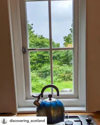 a tea kettle sitting on a stove in front of a window at The Hidden Shepherds Hut- Off Grid Retreat in Castle Douglas